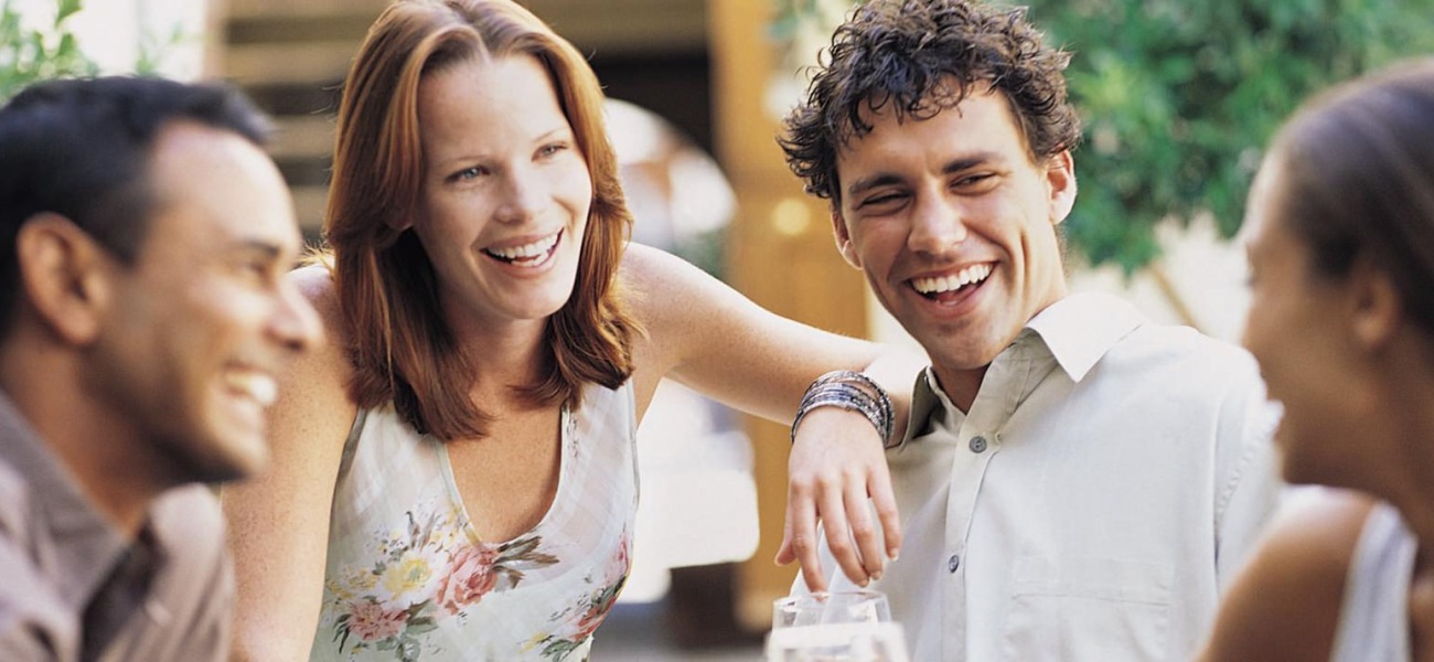 lifestyle image of a group of people laughing and talking outdoors