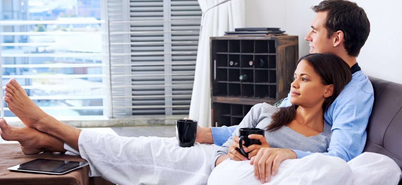 lifestyle image of a couple holding mugs in bed
